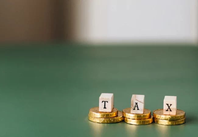 Alphabet blocks spelling out "tax" placed on top of stacked coins against a blurred background