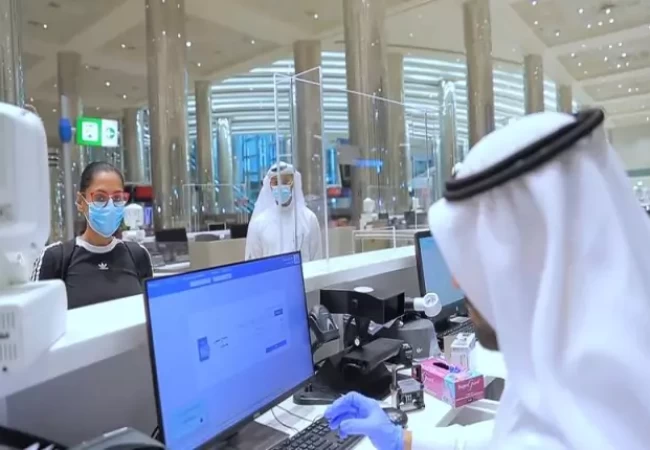 People wearing face masks and gloves in front of a computer