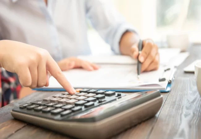 A person using a calculator while reviewing financial documents